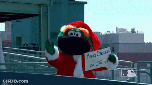A Mascot Dressed In A Santa Suit Is Holding A Sign That Says Merry Christmas In July GIF