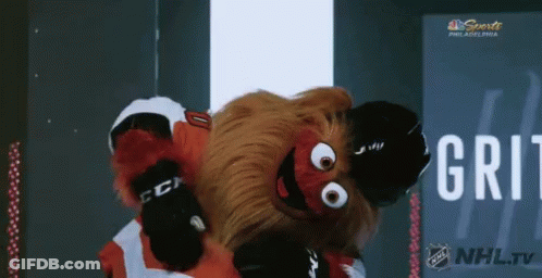 A Mascot For The Philadelphia Flyers Is Dancing In Front Of A Nhl Tv Sign GIF