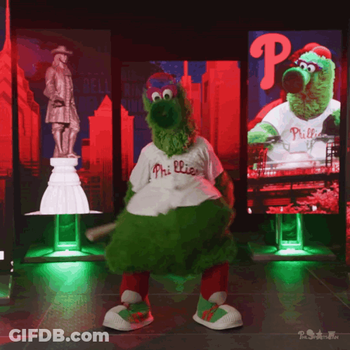 A Mascot For The Phillies Is Dancing In Front Of A Large Screen GIF