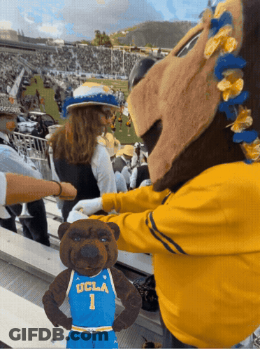 A Mascot For Ucla Is Standing Next To A Stuffed Bear GIF