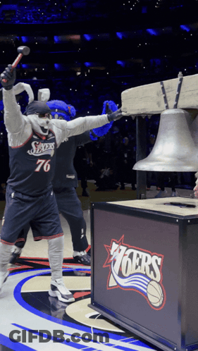 A Mascot Holding A Hammer In Front Of A Sign That Says 76Ers GIF