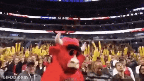A Mascot In A Bull Costume Is Dancing In Front Of A Crowd Of People At A Basketball Game . GIF