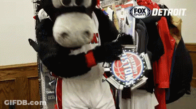 A Mascot In A Detroit Pistons Uniform Holds A Trophy GIF