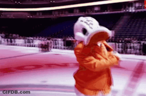 A Mascot In A Duck Costume Is Standing On A Hockey Rink . GIF