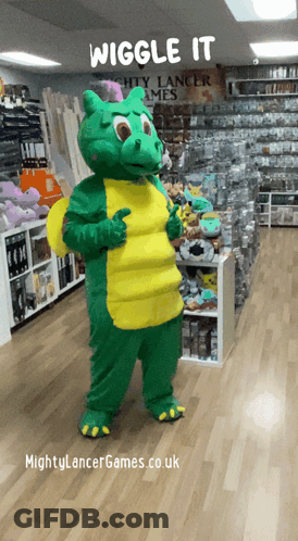 A Mascot In A Green And Yellow Dragon Costume Giving A Thumbs Up In Front Of A Sign That Says Wiggle It GIF