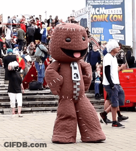 A Mascot In Front Of A Mcm London Comic Con Sign GIF