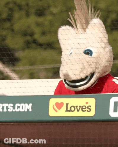 A Mascot Is Behind A Sign That Says Love 'S On It GIF