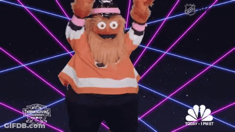 A Mascot Is Dancing In Front Of A Glowing Background That Says Nbc GIF