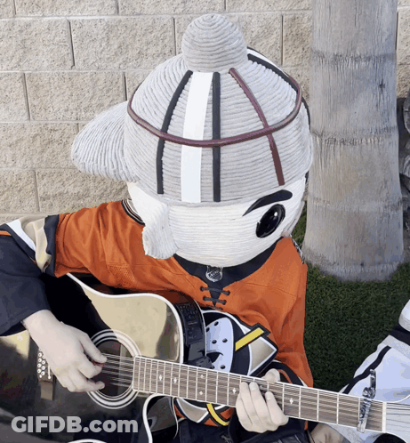 A Mascot Is Playing A Guitar And Wearing An Orange Shirt GIF