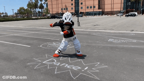 A Mascot Is Standing In A Parking Lot With The Words Dance Written In Chalk GIF