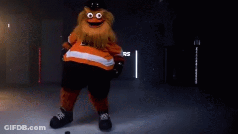A Mascot Is Standing On A Ice Rink With A Puck In His Hand . GIF