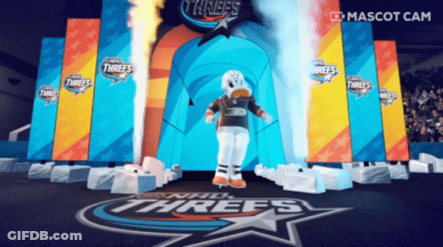 A Mascot Stands In Front Of A Stage That Says Threes GIF