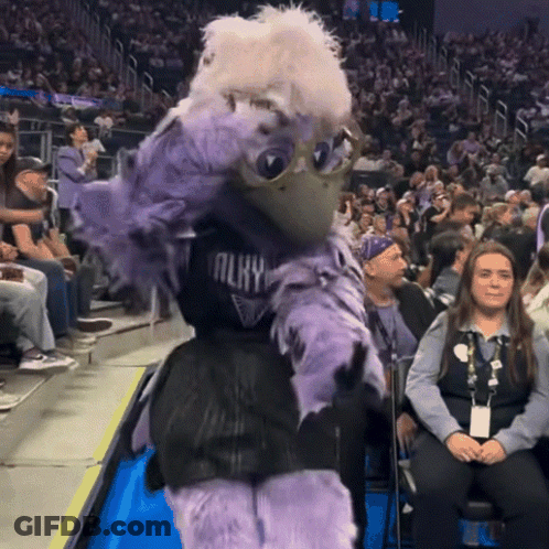 A Mascot Wearing A Jersey That Says Almy Is Dancing In Front Of A Crowd Of People GIF
