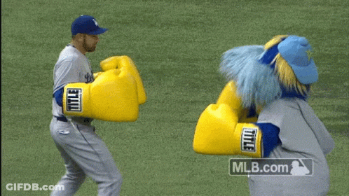 A Mascot Wearing A Pair Of Yellow Boxing Gloves With The Mlb.com Logo In The Corner GIF