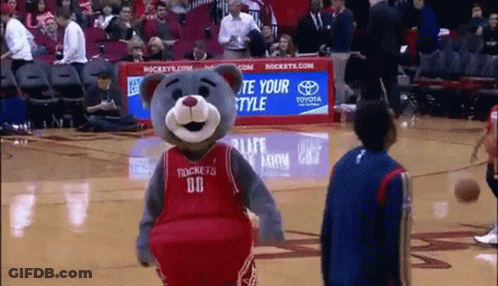 A Mascot Wearing A Rockets Jersey Is Standing On A Basketball Court . GIF