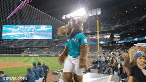 A Mascot Wearing A Seahawks Jersey Stands On A Podium At A Baseball Game GIF