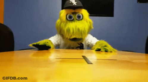 A Mascot Wearing A White Sox Hat Sits At A Conference Table GIF
