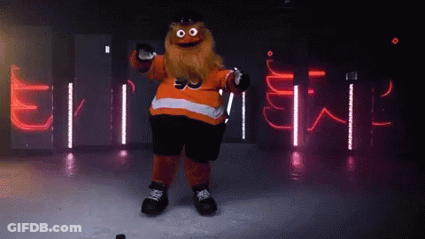 A Mascot With A Beard Is Holding A Hockey Puck In Front Of A Sign That Says ' Flyers ' GIF