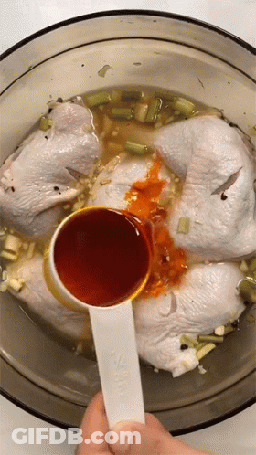 A Measuring Spoon Is Being Used To Pour Sauce Into A Bowl Of Chicken GIF