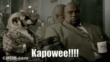Meerkat In Suit Sitting Next To Man In Suit GIF