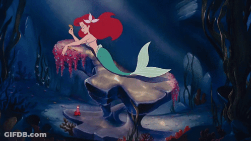A Mermaid Is Laying On A Rock In The Ocean GIF