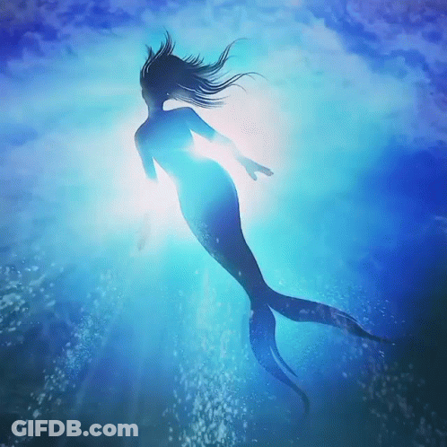 A Mermaid Is Swimming In The Ocean With The Sun Shining Through The Water GIF