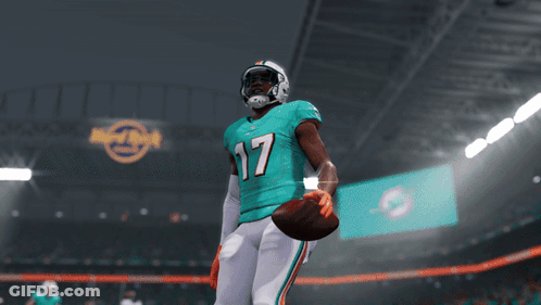 A Miami Dolphins Football Player Stands In Front Of A Touchdown Banner GIF