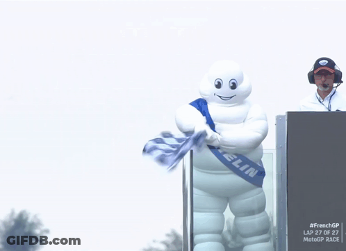 A Michelin Mascot Is Holding A Flag GIF