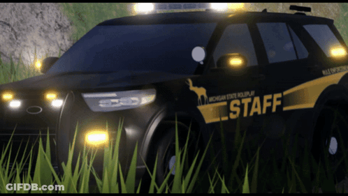 A Michigan State Police Car Is Parked In A Grassy Field GIF