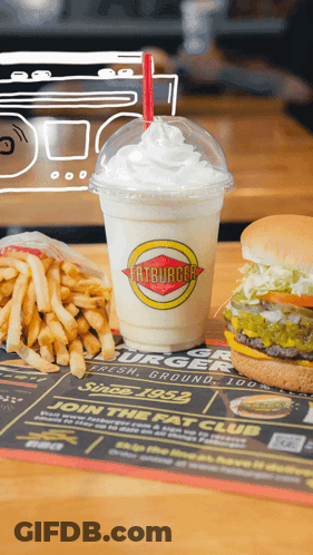 A Milkshake From Fatburger Sits On A Table With French Fries And A Hamburger GIF