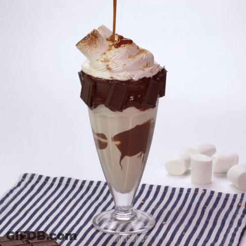 A Milkshake With A Chocolate Bar On Top And Whipped Cream GIF