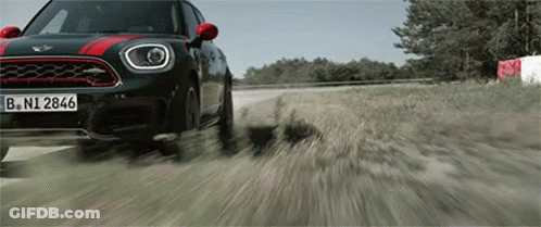 A Mini Cooper Driving Down A Dirt Road GIF