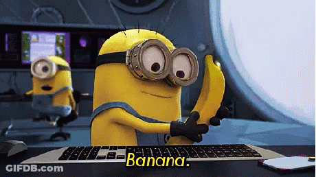 A Minion Holding A Banana In Front Of A Keyboard That Says Banana On It GIF
