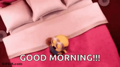 A Minion Is Laying On Top Of A Bed With The Words `` Good Morning ! '' GIF