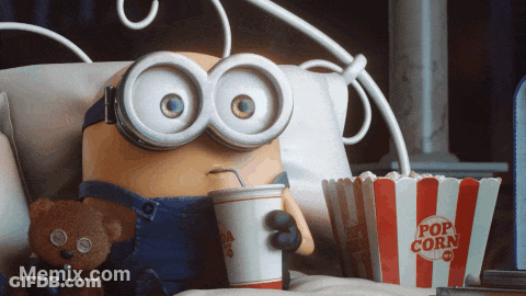 A Minion Is Sitting On A Bed With A Cup Of Soda And A Bucket Of Popcorn GIF