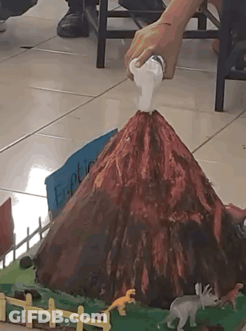 A Model Of A Volcano With A Sign That Says Eruption GIF