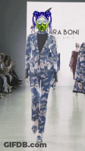 A Model Walks Down A Runway Wearing A Blue Suit And A Green Mask By Taraboni GIF