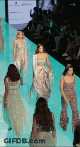 A Model Walks Down The Runway At A Fashion Show In Front Of A Sign That Says Ecovero GIF