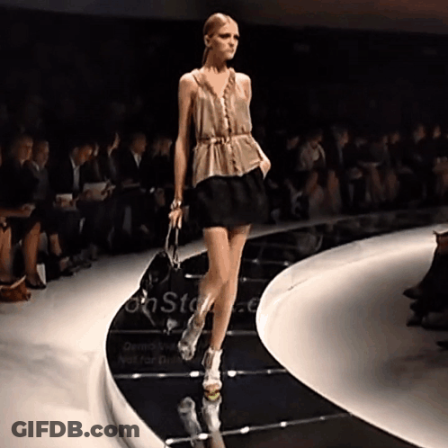 A Model Walks Down The Runway At A Fashion Show With A Sign That Says On Stage GIF