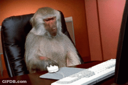 A Monkey Is Sitting At A Desk With A Computer Mouse And Keyboard GIF