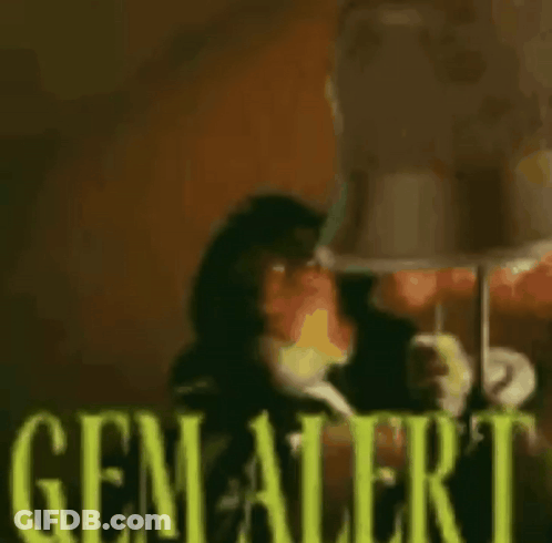 A Monkey Is Sitting In Front Of A Lamp With The Words `` Gem Alert '' Written In Yellow Letters . GIF
