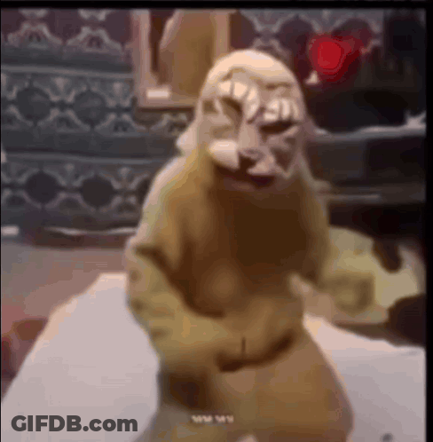 A Monkey With A Mask On Its Face Is Dancing On A Table . GIF