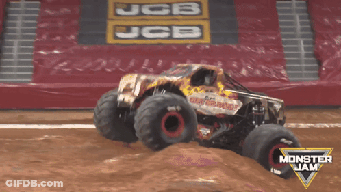 A Monster Jam Truck Is Jumping Over A Dirt Field GIF