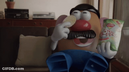A Mr Potato Head Is Sitting On A Couch Eating A Bag Of Saltines GIF