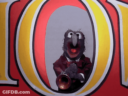 A Muppet Is Playing A Trumpet In Front Of The Letter O. GIF