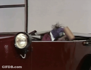 A Muppet Is Sitting In A Red Car With Its Head Out The Window . GIF