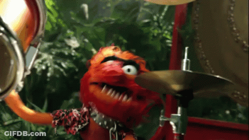 A Muppet Playing A Drum Set With A Jungle Background GIF