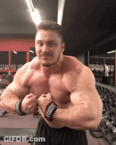 A Muscular Man Is Posing For A Picture In A Gym . GIF