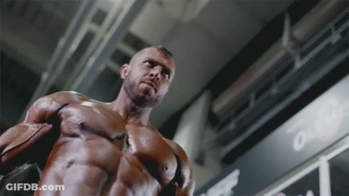 A Muscular Man Is Standing In Front Of A Sign That Says " Out " GIF