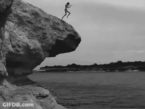 A Naked Man Is Jumping Off A Cliff Into The Water . GIF
